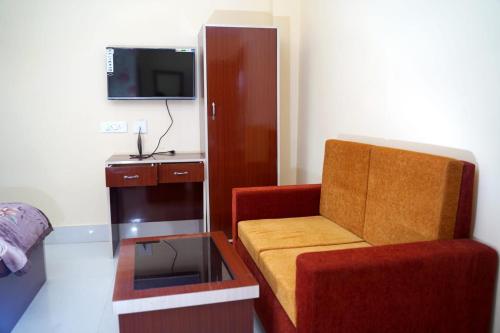 Habitación pequeña con silla y TV. en Hotel Royal Sunview en Digha