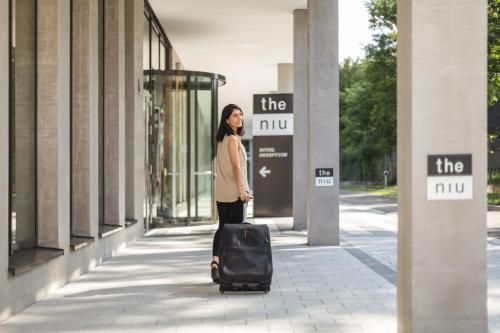 a woman walking down a sidewalk with a suitcase at Holiday Inn - the niu, Loco Munich North by IHG in Munich