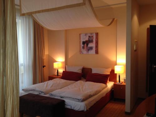 Bett in einem Hotelzimmer mit zwei Lampen in der Unterkunft Ringhotel Bundschu in Bad Mergentheim