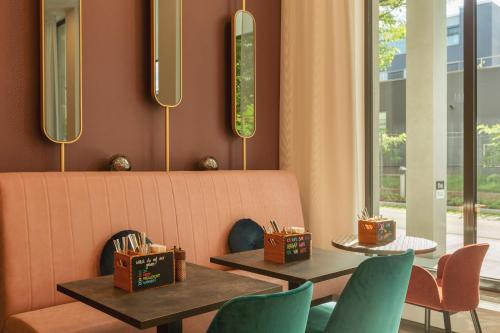 a restaurant with two tables and chairs and a bench at Holiday Inn - the niu, Loco Munich North by IHG in Munich