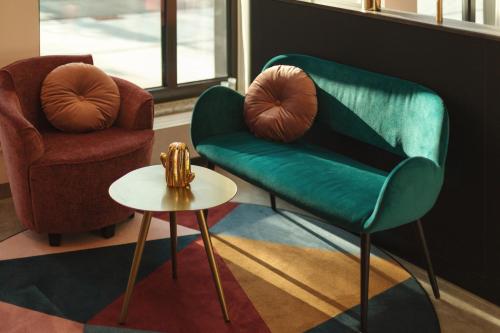 a living room with a green chair and a table at Holiday Inn - the niu, Loco Munich North by IHG in Munich