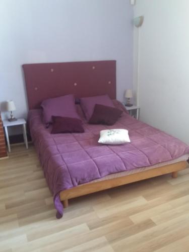 een groot paars bed met paarse lakens en kussens bij Quai de l ' Arnette in Mazamet