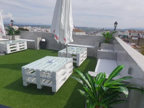 a patio with two white tables and an umbrella at Hostal Málaga in Arcos de la Frontera