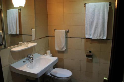 a bathroom with a sink and a toilet and towels at Hotel Marqués de Santillana in Torrelavega