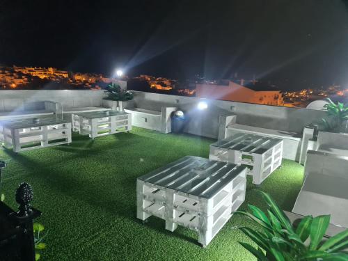 a patio with white benches on the roof at night at Hostal Málaga in Arcos de la Frontera