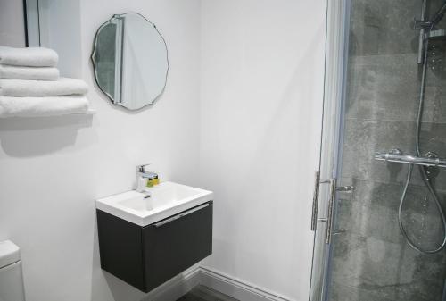a white bathroom with a sink and a mirror at Oswald House deluxe 2 bedroom apartment in Harrogate