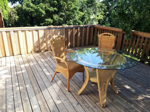 a glass table and two chairs on a deck at Ein Bett im Kornfeld - Haus Weitblick - mit Innenpool in Schönfeld