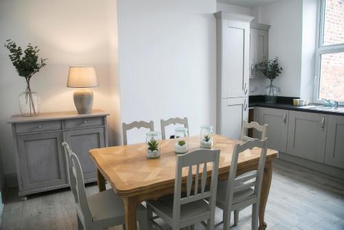 a dining room with a wooden table and chairs at Oswald House deluxe 3 bedroom apartment in Harrogate