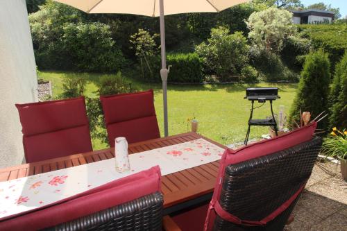 a table and chairs with an umbrella and a grill at Ferienwohnung Raithel in Bischofsgrün