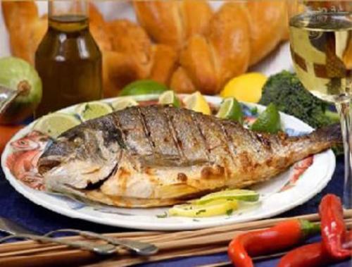a plate of fish on a table with a glass of wine at CONACUL SARBESC in Sviniţa