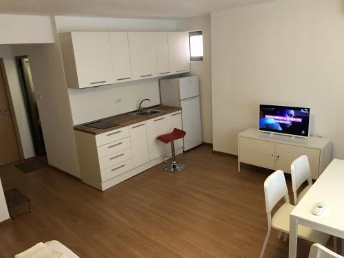 una pequeña cocina con armarios blancos y TV. en Aparthotel Elly en Pomorie