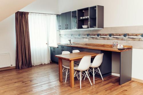 a kitchen with a wooden table and white chairs at Verhovel Hotel in Verkhovyna