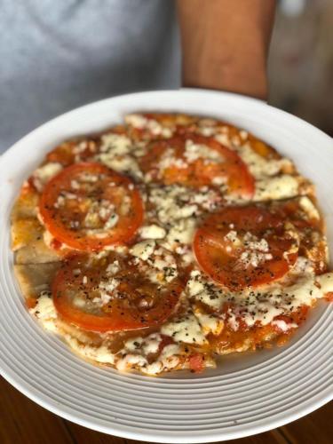 a pizza with tomatoes on a plate on a table at Seaside Garden Ecolodge Mompiche in Mompiche