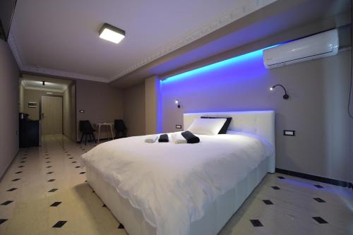 - une chambre avec un grand lit blanc et une lumière bleue dans l'établissement Pietra Mare Suites, à Patras