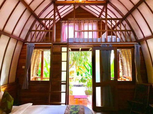 a room with a large glass door in a house at Cotton Tree Cottages in Gili Trawangan
