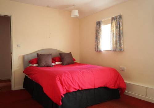 1 dormitorio con cama roja y ventana en Edge of Exmoor Garden Flat, dog friendly, sleeps 2 - 4 en East Anstey