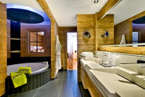 La salle de bains est pourvue de 3 lavabos, d'une baignoire et d'une baignoire. dans l'établissement PETE - Alpine Boutique Hotel, à Sankt Anton am Arlberg