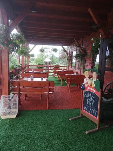 a restaurant with picnic tables and a sign in the grass at Pensiunea Armand in Supuru de Jos