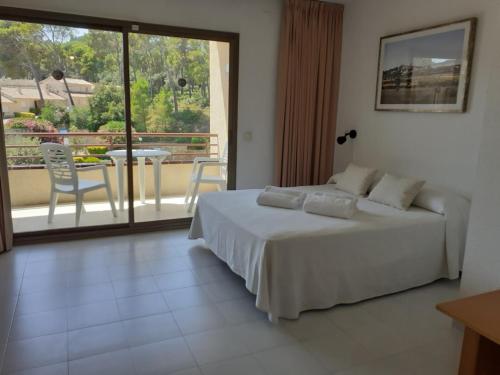 パルスにあるAparthotel Golf Beachのベッドルーム1室(ベッド1台付)、バルコニー(テーブル付)