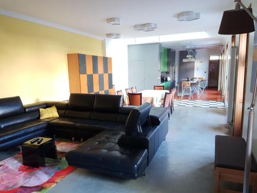 ein Wohnzimmer mit einem schwarzen Ledersofa und Stühlen in der Unterkunft spacieuse maison urbaine proche du centre ville in Béthune