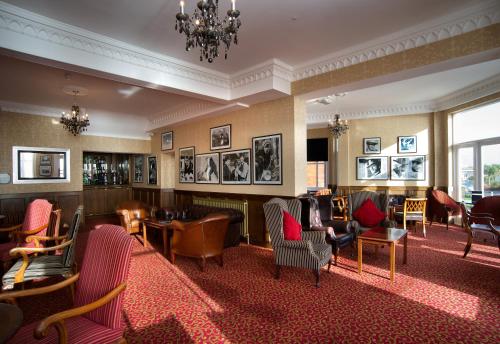 a hotel lobby with chairs and tables and a chandelier at Langham Hotel Eastbourne in Eastbourne