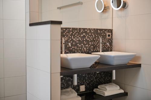 a bathroom with two sinks on a shelf with towels at Hotel De Lindeboom in Den Burg