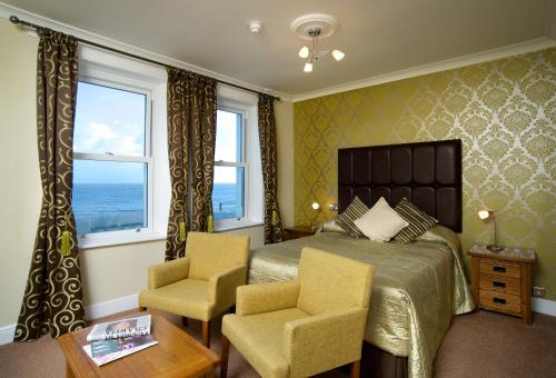 een slaapkamer met een bed en 2 stoelen bij Langham Hotel Eastbourne in Eastbourne