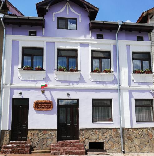 a purple building with windows and flowers in the window boxes at Хаджи Марковата къща за гости гр.Дряново in Dryanovo