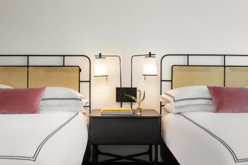 a bedroom with two beds and a table with a lamp at Kimpton Hotel Fontenot by IHG in New Orleans