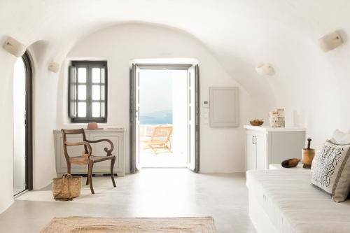 a white living room with a table and a chair at Armenaki in Oia