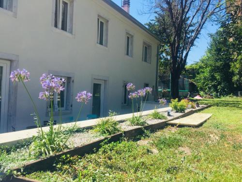 un giardino di fronte a una casa bianca con fiori viola di B&B MonteCengio a Trieste