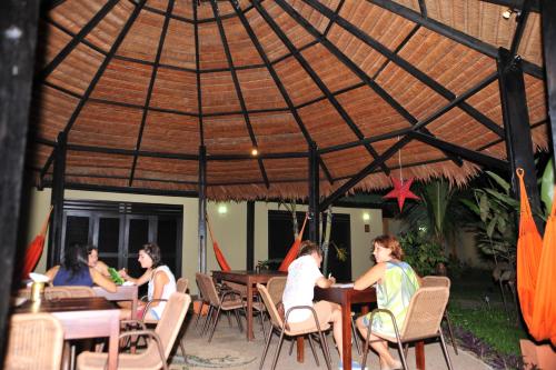 un grupo de personas sentadas en mesas bajo un paraguas en Hotel Amazon Bed And Breakfast, en Leticia