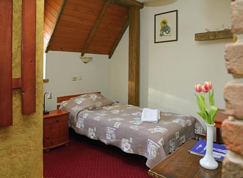 ein Schlafzimmer mit einem Bett und einem Tisch mit einer Blumenvase in der Unterkunft Jaś Wędrowniczek in Rymanów