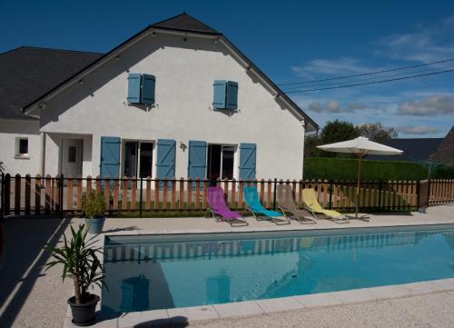 a house with a swimming pool with chairs and an umbrella at Les 3 Edelweiss - GITE 1 OU GITE 2 in Arette