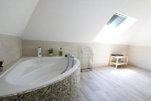 La salle de bains est pourvue d'une grande baignoire et d'une lucarne. dans l'établissement Colmar City Center - Apartment Duplex MARIGNY - BookingAlsace, à Colmar