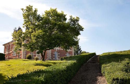 un bâtiment en briques avec un arbre devant lui dans l'établissement Chateau de Joyeux - Chambres d'Hotes, à Joyeux