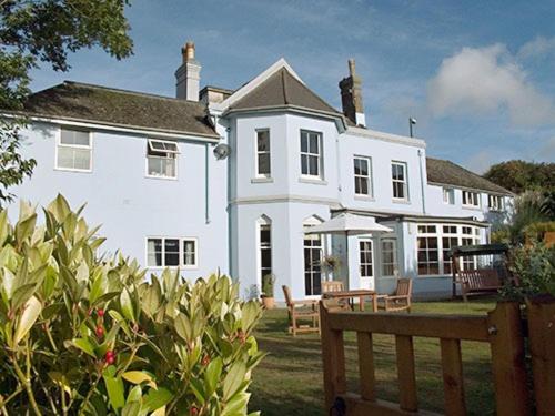 a large white house with a bench in front of it at amber house hotel in Paignton