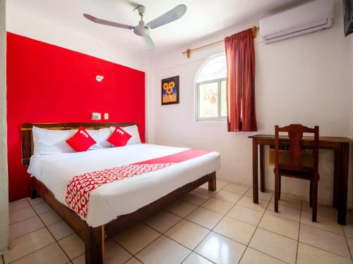 1 dormitorio con cama y pared roja en OYO Hotel Betsua Vista Hermosa, Huatulco en Santa Cruz - Huatulco