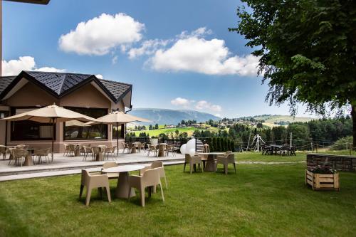 un patio con mesas, sillas y sombrillas en Linta Hotel Wellness & Spa, en Asiago