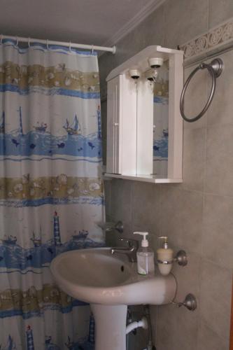a bathroom with a sink and a shower curtain at Koula's Place in Elafonisos