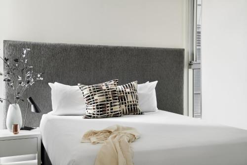 a bedroom with a white bed with pillows at Punthill South Yarra Grand in Melbourne