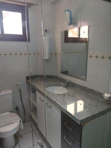 a bathroom with a sink and a toilet and a mirror at Apart Hotel Serantes in Natal
