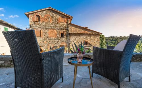 a patio with three chairs and a table and a building at Casa Collodi Castello in Collodi