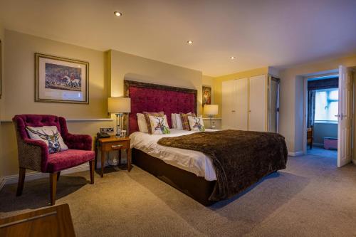 a bedroom with a large bed and a chair at The Feathers Hotel, Helmsley, North Yorkshire - The Coaching Inn Group in Helmsley