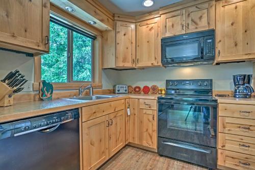 a kitchen with wooden cabinets and a stove and a microwave at Private Leavenworth Cabin with Mtn Views and Fire Pit in Leavenworth