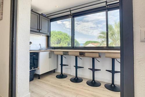 une cuisine avec un comptoir et une grande fenêtre dans l'établissement Les Terrasses fleuries du Port, à Saint-Cyprien