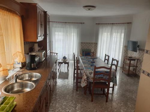 a kitchen with a sink and a table with chairs at HOMELIDAYS CLARA NAZARE in Nazaré