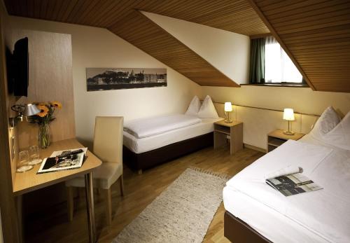 a hotel room with two beds and a table and a desk at HartlWirt Gasthof-Hotel in Salzburg