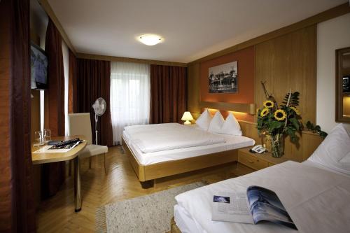 a hotel room with a bed, chair, and a tv at HartlWirt Gasthof-Hotel in Salzburg