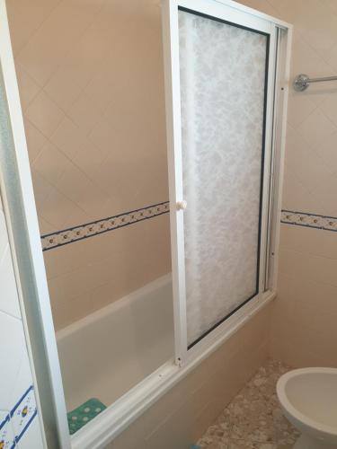 um chuveiro com uma porta de vidro na casa de banho em HOMELIDAYS CLARA NAZARE em Nazaré